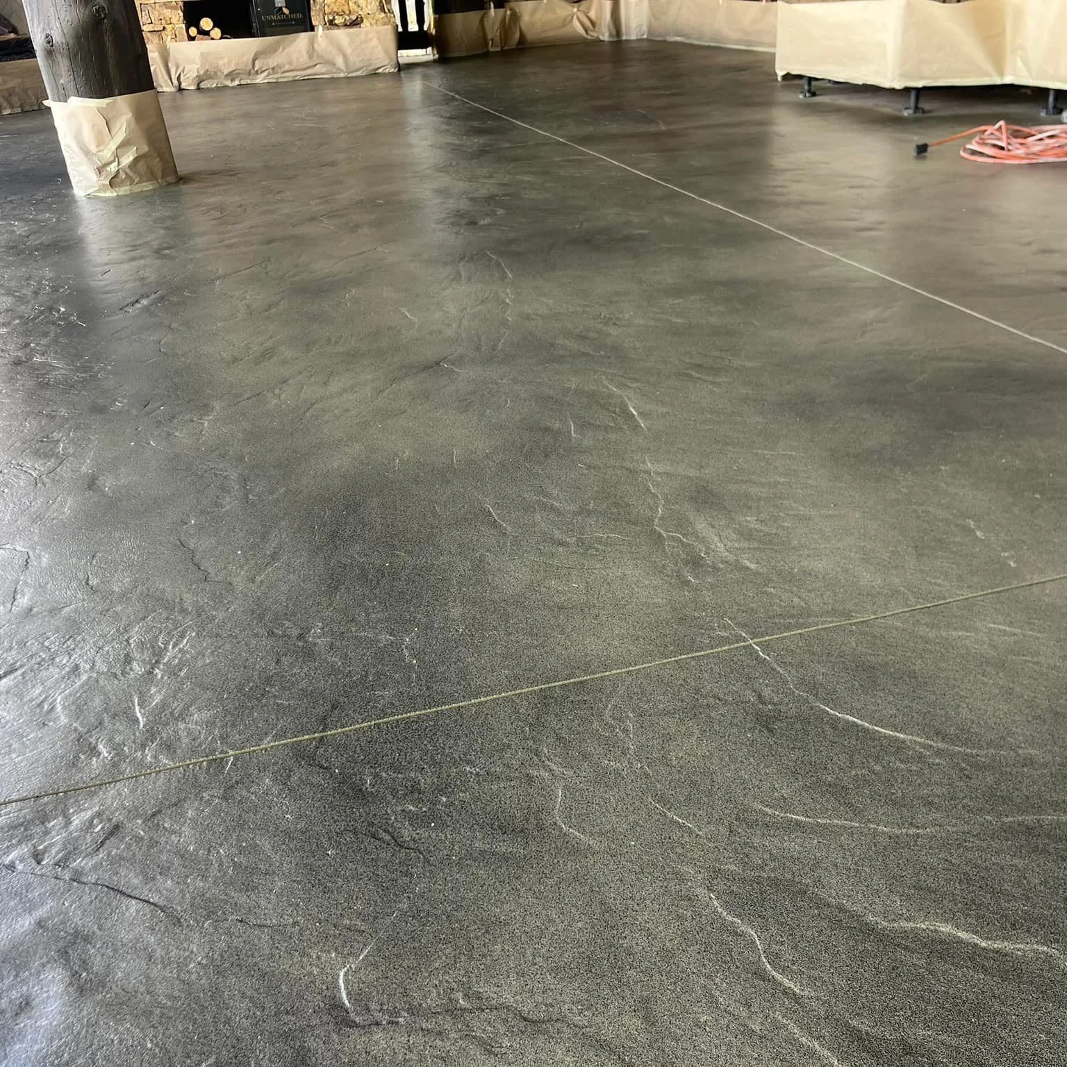A resurfaced backyard patio in Colorado Springs featuring a stamped concrete overlay with a natural stone pattern and earth-tone coloring. The decorative concrete surface surrounds an outdoor seating area against a backdrop of Colorado's high-elevation landscape.